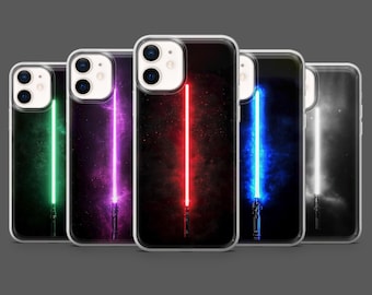 May include: A collection of clear phone cases featuring colorful lightsaber designs. Each case displays a different colored lightsaber: green, purple, red, blue, and white, set against a dark, starry background.