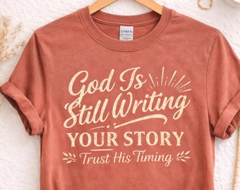 Camiseta cristiana inspiradora: «Dios sigue escribiendo tu historia». Confía en su tiempo. Camiseta de fe.