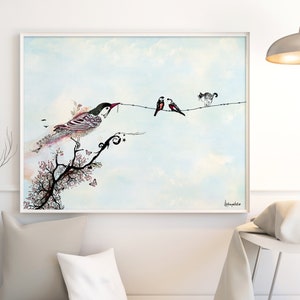 A framed watercolor painting of a bird perched on a branch with two other birds on a wire. The painting is set against a light blue sky with white clouds. The painting is framed in a white frame and is hanging on a white wall.