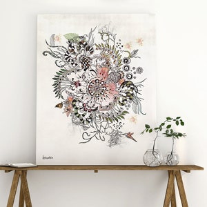 black and white floral illustration with pink and green accents on a white background. The illustration is framed and hanging on a white wall above a wooden table with two clear glass vases containing green plants.