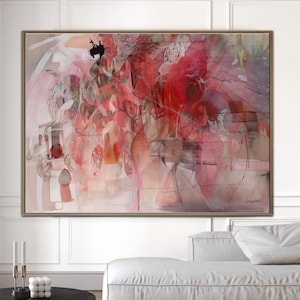 May include: Abstract painting with a wooden frame. The artwork features a blend of red, pink, and beige hues, with black accents and a signature in the lower right corner. The painting is displayed above a white sofa.