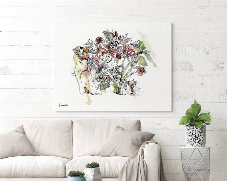 A canvas art print featuring a whimsical illustration of an elephant adorned with flowers and foliage. The artwork uses a watercolor style with black outlines and splashes of color, including red, yellow, and green. The print is displayed on a white wall above a sofa.