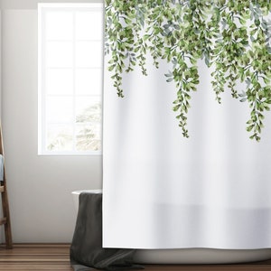 May include: White shower curtain with a green watercolor floral design of leafy vines hanging down from the top. The design is on a white background.
