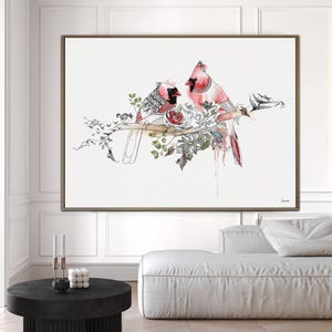 A framed horizontal wall art print featuring two red cardinals perched on a branch. The birds are depicted with detailed black ink line work and watercolor accents, surrounded by botanical illustrations of leaves and flowers.