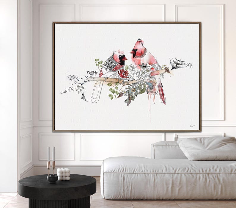 A framed horizontal wall art print featuring two red cardinals perched on a branch. The birds are depicted with detailed black ink line work and watercolor accents, surrounded by botanical illustrations of leaves and flowers.