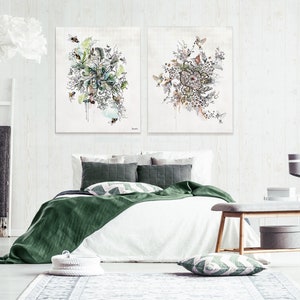 Two abstract watercolor paintings with floral and bird motifs, hanging above a white bed with green bedding and pillows in a bedroom setting.
