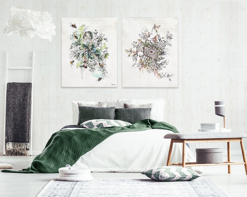 Two abstract watercolor paintings with floral and bird motifs, hanging above a white bed with green bedding and pillows in a bedroom setting.