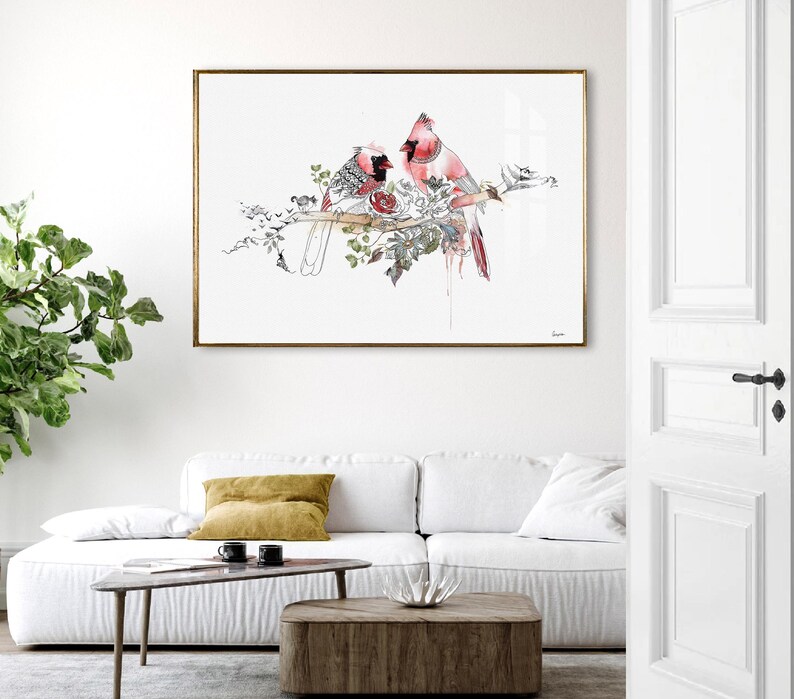 A rectangular wall art print featuring a watercolor illustration of two red cardinal birds perched on a branch surrounded by detailed botanical sketches in black ink, all set against a clean white background within a thin gold frame.