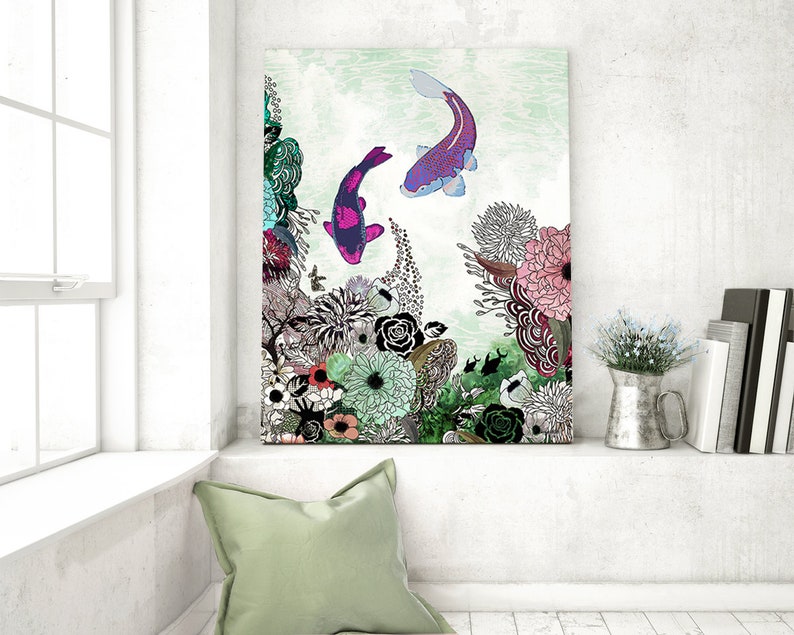 A colorful abstract painting of two purple and pink fish swimming in a green and white floral background. The painting is framed and hanging on a white wall.