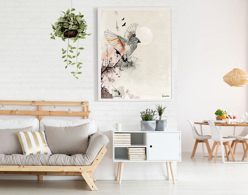 A framed illustration of a bird in flight with a moon in the background. The bird is drawn in black and white with orange and pink accents. The background is a light beige with a subtle texture. The illustration is framed in a white frame.