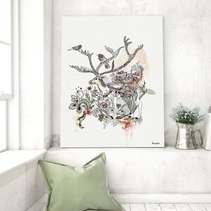 Canvas print featuring a watercolor and ink illustration of a deer surrounded by floral elements and birds. The artwork is predominantly in shades of gray, black, and beige, with accents of orange and pink. The deer is centrally positioned, with its antlers extending outward. The style is whimsical and nature-inspired. The artist's signature is visible in the bottom right corner.
