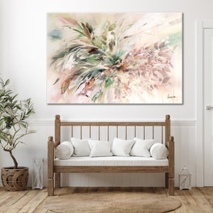 A large abstract watercolor painting with a white background and shades of pink, green, and brown. The painting features a cluster of leaves and branches in the center, with a few leaves extending out to the edges of the canvas. The painting is signed in the bottom right corner with the name 'Gingko'. The painting is hanging on a white wall above a wooden bench with white cushions.