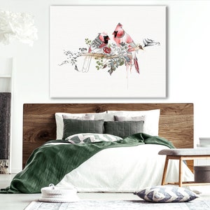 A watercolor painting of two red cardinals perched on a branch with white flowers. The birds are facing each other and the background is white.