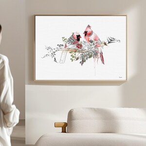 A framed horizontal wall art print featuring two red cardinal birds perched on a branch. The illustration incorporates detailed black ink line work, watercolor accents in shades of red and green, and botanical elements on a white background.
