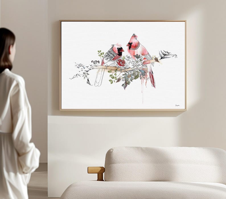 A framed horizontal wall art print featuring two red cardinal birds perched on a branch. The illustration incorporates detailed black ink line work, watercolor accents in shades of red and green, and botanical elements on a white background.