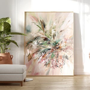 Large abstract painting in a gold frame. The artwork features a blend of green, pink, and brown brushstrokes, creating a floral or botanical theme. The painting is displayed in a well-lit room with a neutral color palette.