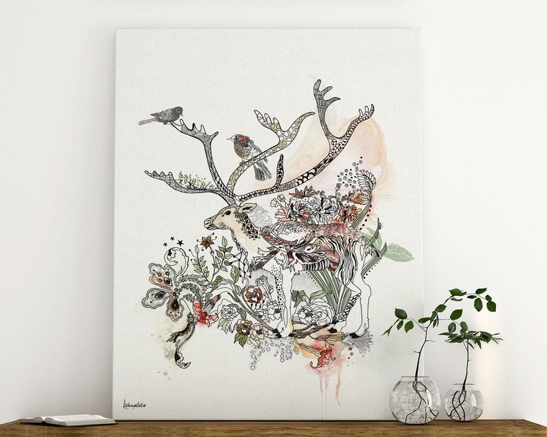 Canvas print featuring a detailed illustration of a reindeer adorned with intricate line art and watercolor accents. The reindeer is surrounded by a whimsical arrangement of flowers, leaves, and birds, creating a nature-inspired design. The artwork is predominantly in shades of beige, brown, and green, with pops of color from the flowers and birds. The artist's signature is subtly placed in the bottom left corner.