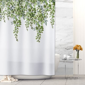 May include: White shower curtain with a green floral pattern of hanging vines. The curtain is in a bathroom with a white tiled wall and a white bathtub.