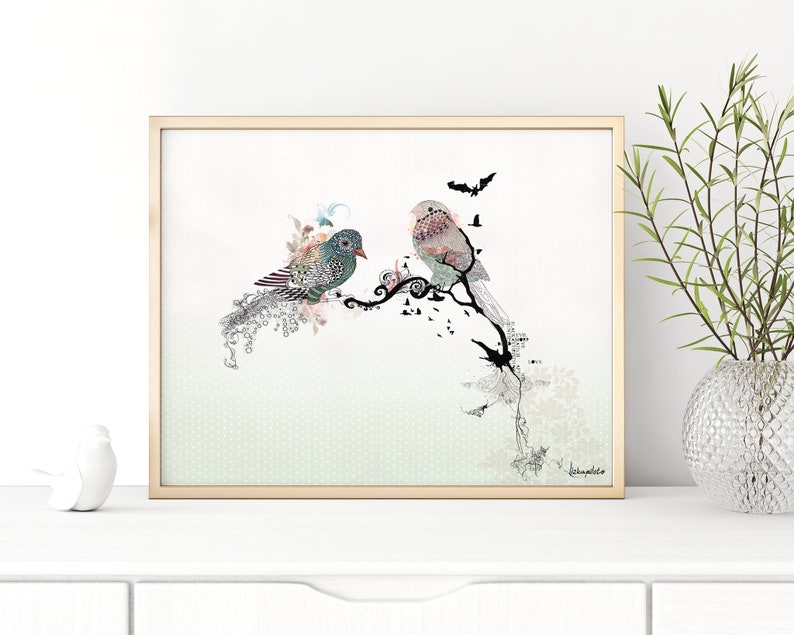A framed print of two stylized birds perched on a branch with black and white floral accents. The background is a light green with a subtle pattern. The print is signed "K.Humphries".