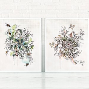Two framed prints with abstract floral designs in black and white with splashes of color. The designs feature birds and bees.
