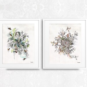 Two framed prints with intricate black and white drawings of floral arrangements with birds and bees. The prints have a watercolor background with shades of blue, green, and pink.