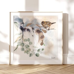 Framed watercolor painting featuring a sparrow perched on a eucalyptus branch. The artwork showcases soft, muted colors of beige, light blue, and green.  The bird is brown and detailed. The leaves are a soft green and the background is a light beige with subtle blue washes. The artist's signature is visible in the bottom right corner.
