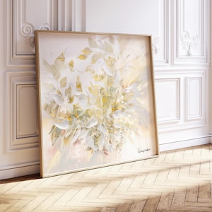 A large, square framed painting featuring an abstract floral design in soft, muted tones. The artwork showcases a bouquet of white and yellow leaves with subtle pink accents. The painting is leaning against a white wall with decorative molding.