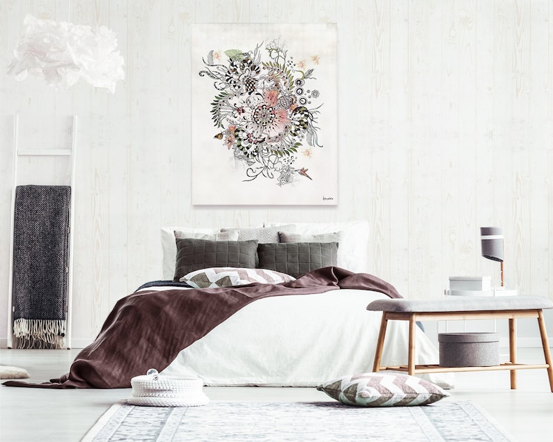 A white bed with a brown blanket and pillows. The bed is in a bedroom with a white wall and a white rug. There is a painting of a floral design on the wall above the bed. A wooden bench is in the foreground with a gray storage box on the bottom shelf.