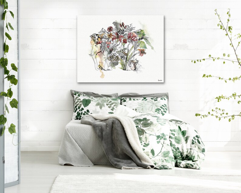 A watercolor painting of an elephant with a floral headdress hangs above a bed with green and white floral bedding. A gray blanket and pillows complete the bed set. The room has white walls and a white floor.