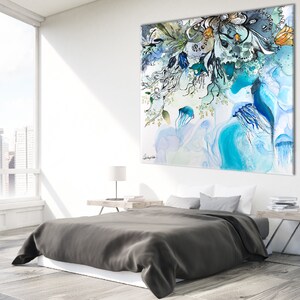 Abstract watercolor painting featuring a blue, green, and white color scheme. The painting depicts a cluster of jellyfish and floral elements. The painting is displayed on a wall above a gray bed with white bedding.