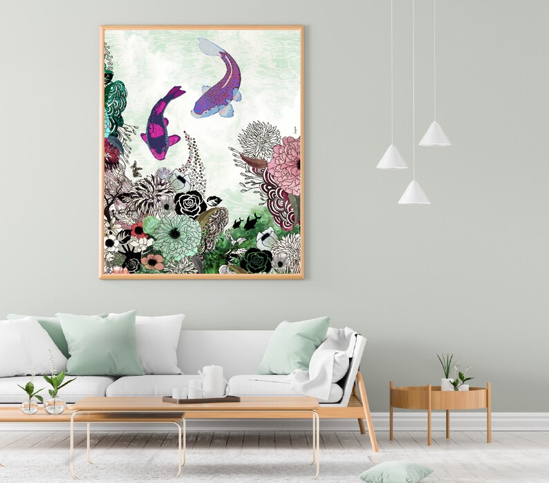 A framed print of a colorful illustration of koi fish swimming in a garden with pink, green, and white flowers. The print is hanging on a light green wall above a white couch with light green throw pillows.