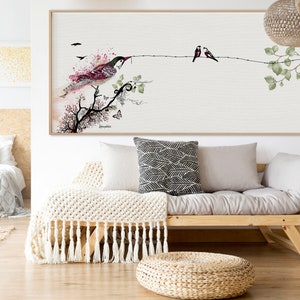 framed watercolor painting of a bird perched on a branch with two smaller birds on a branch above. The painting has a light background with pink and green accents.
