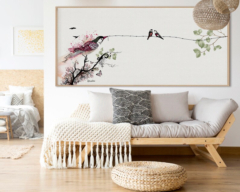framed watercolor painting of a bird perched on a branch with two smaller birds on a branch above. The painting has a light background with pink and green accents.