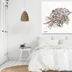 May include: A white canvas print with a black and white floral design with pink and green accents. The design features a variety of flowers, leaves, and branches. The print is framed in a white frame and is hanging on a white wall.