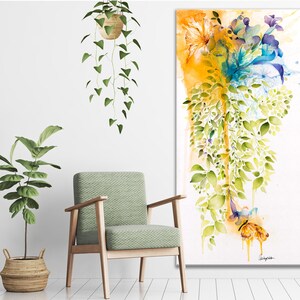 Watercolor painting of a floral arrangement with yellow, blue, and green hues. The flowers are cascading down a white background with a yellow and orange wash at the top. The painting is framed and ready to hang.