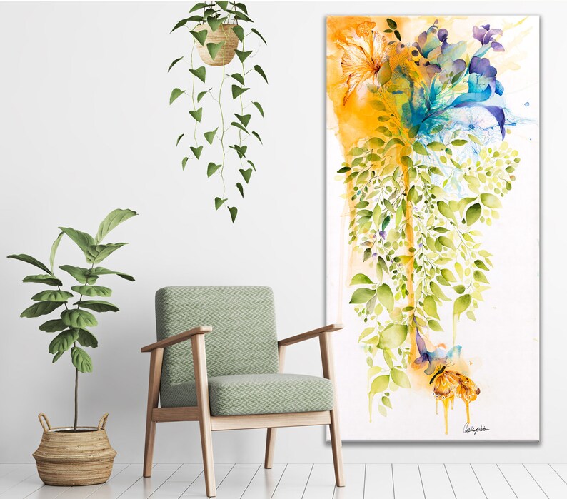 Watercolor painting of a floral arrangement with yellow, blue, and green hues. The flowers are cascading down a white background with a yellow and orange wash at the top. The painting is framed and ready to hang.