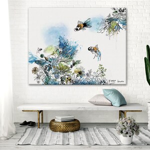 watercolor painting of a white background with blue, green, and yellow floral designs and two gold fish. The painting is framed and hanging on a white brick wall.