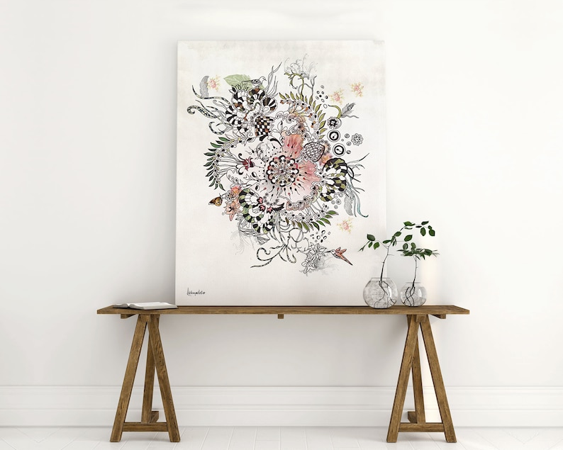black and white floral illustration with pink and green accents on a white background. The illustration is framed and hanging on a white wall above a wooden table with two clear glass vases containing green plants.