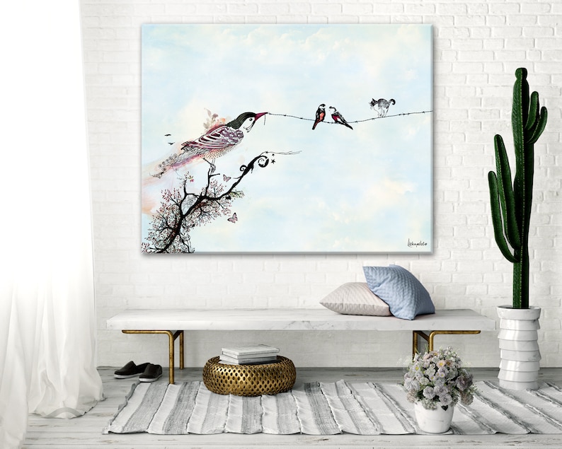 A watercolor painting of a bird perched on a branch with two other birds on a wire. The painting is framed and hanging on a white brick wall. The painting is in a living room setting with a white couch, a cactus plant, and a small potted plant with white flowers.