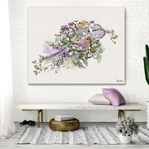 A white canvas print with a watercolor painting of a floral arrangement. The flowers are in shades of pink, purple, and yellow. The painting is surrounded by a white frame and is hanging on a white brick wall. The painting is in a living room setting with a white bench, a gold metal stool, and a potted cactus.