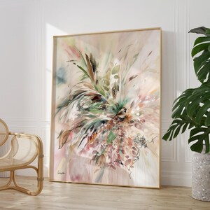 Large framed abstract art print featuring a floral design in soft pastel colors. The artwork includes green, pink, and brown tones, with a light beige background. The frame is a light wood color, and the overall style is modern.