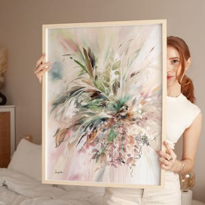 Abstract art print in a light wooden frame. The artwork features a vibrant mix of colors, including green, pink, and beige, with a focus on botanical elements. The painting has a soft, watercolor-like quality, with delicate lines and textures.