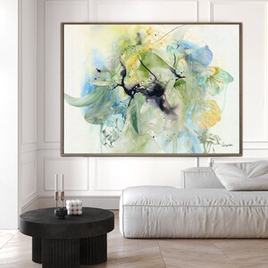 Abstract watercolor painting with shades of blue, green, and yellow. The painting features a large, central flower-like shape with delicate brushstrokes and a black splatter effect.