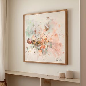 A framed watercolor painting featuring a floral design in soft pastel colors. The artwork includes shades of pink, green, and orange, with a wooden frame. The painting is mounted on a white wall.