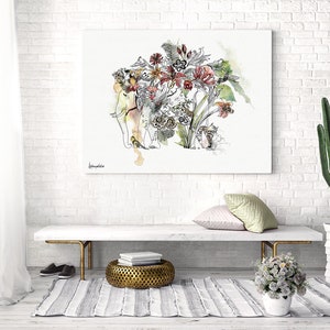 An artistic watercolor painting of an elephant with floral elements. The artwork is displayed on a white brick wall, with a bench, rug, and cactus in the foreground. The painting has a light color palette with red, green, and yellow accents.