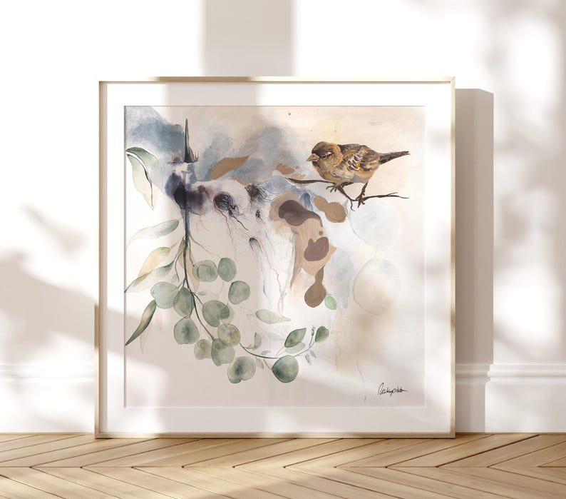 Framed watercolor painting featuring a sparrow perched on a branch of eucalyptus leaves. The artwork uses soft, muted colors, including pale blues, greens, and browns. The background is a light beige with abstract shapes and watercolor washes. The overall style is delicate and nature-inspired. The artist's signature is visible in the bottom right corner.