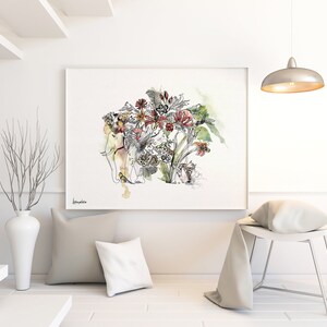 Watercolor art print featuring an elephant adorned with a floral arrangement. The artwork showcases a mix of red, yellow, and green flowers with intricate black line details. The print is framed and displayed in a modern, minimalist interior setting.