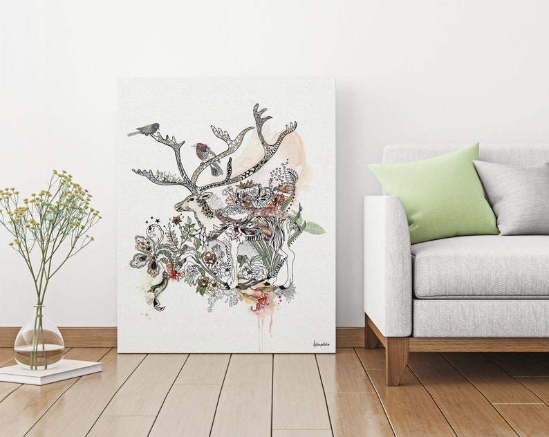 Canvas print featuring a detailed ink drawing of a reindeer surrounded by floral elements and birds. The reindeer is depicted in black ink with subtle watercolor washes of peach and beige. The floral elements are intricate and detailed, with a mix of leaves, flowers, and butterflies in varying shades of brown, green, and pink. Three small birds are perched on the reindeer's antlers. The overall style is whimsical and nature-inspired, with a touch of bohemian flair.