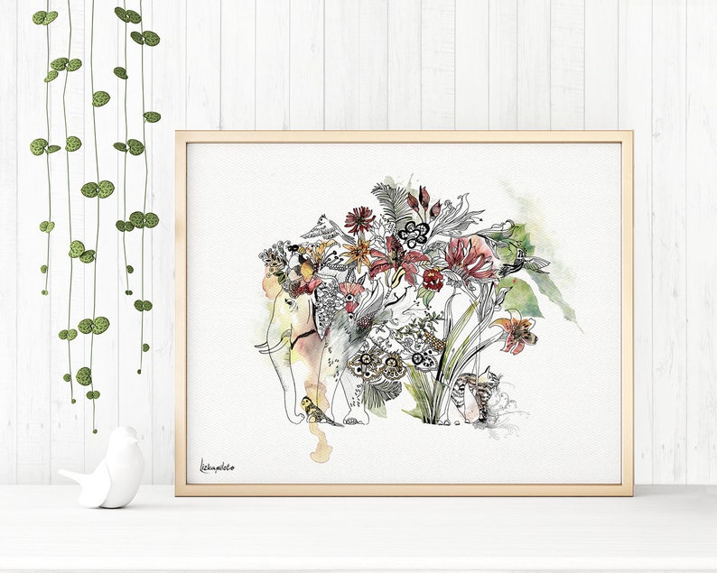 A framed watercolor print featuring an elephant adorned with a floral headdress. The artwork showcases a blend of botanical elements and animal imagery, with a soft color palette of yellows, reds, and greens. The frame is a light wood color.