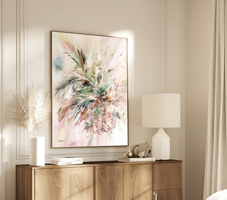 Abstract floral art print in a wooden frame. The artwork features a soft color palette of pink, green, and brown, with a focus on botanical elements. The painting is displayed above a wooden cabinet.